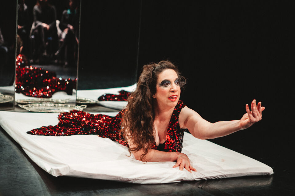 Female performer lying on the floor of a theatre stage